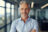 Happy middle aged business man ceo standing in office arms cross